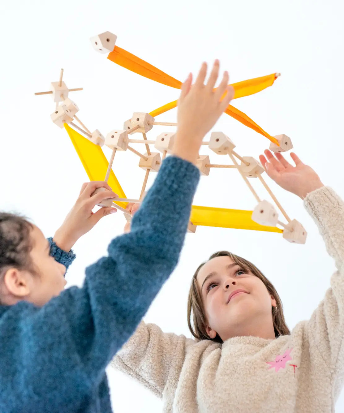 Children holding up a helicopter made from various wooden poles and blocks out of the Trigonos mini large construction set 