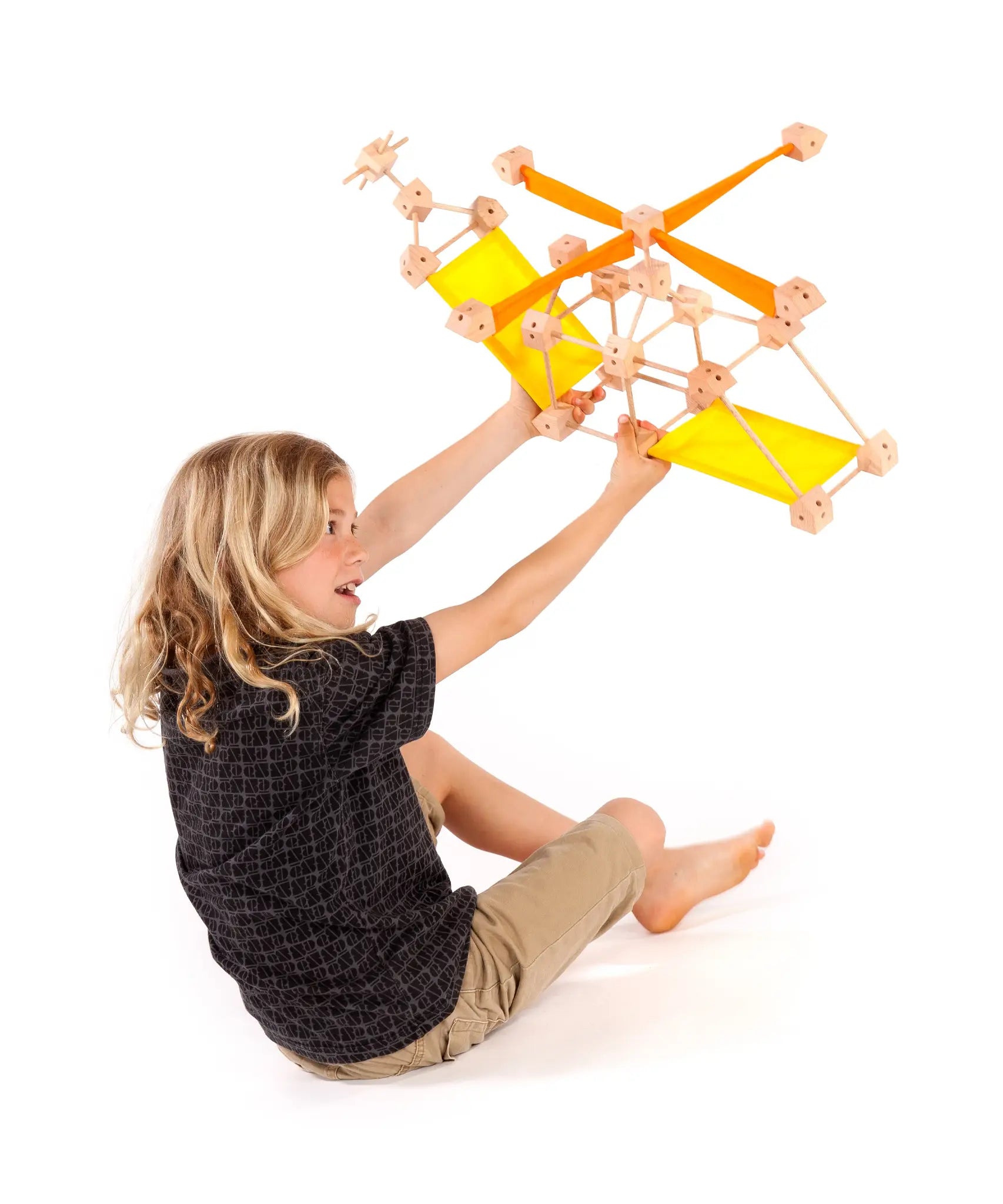 Child holding a helicopter made from various wooden poles and blocks from the Trigonos mini large construction set 