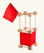 A tower build using pieces from the Trigonos wooden mini construction kit with red cotton sheets