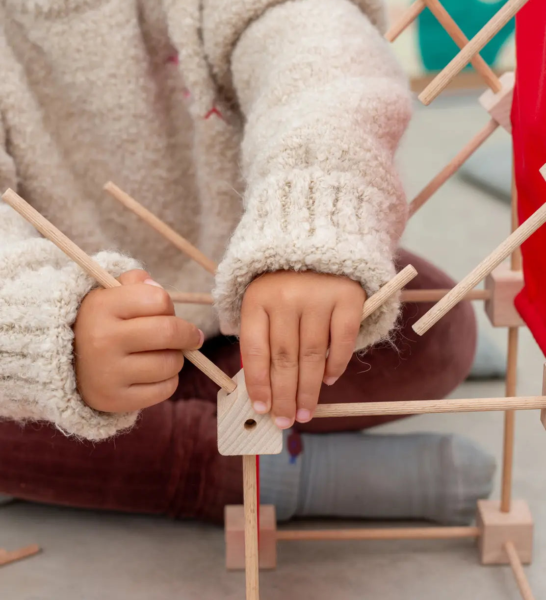 Child building a structure using the poles into the corner blocks from the Trigonos mini construction kit