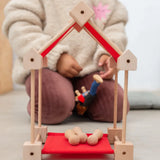A simple house build from the Trigonos wooden mini construction kit with small balls inside on a red sheet
