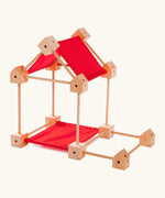 Trigonos wooden mini construction set showing a simple house build made from poles, cube corner blocks and red cotton sheets