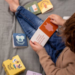 Child sat on a blanket reading Trixie Little Library board books.