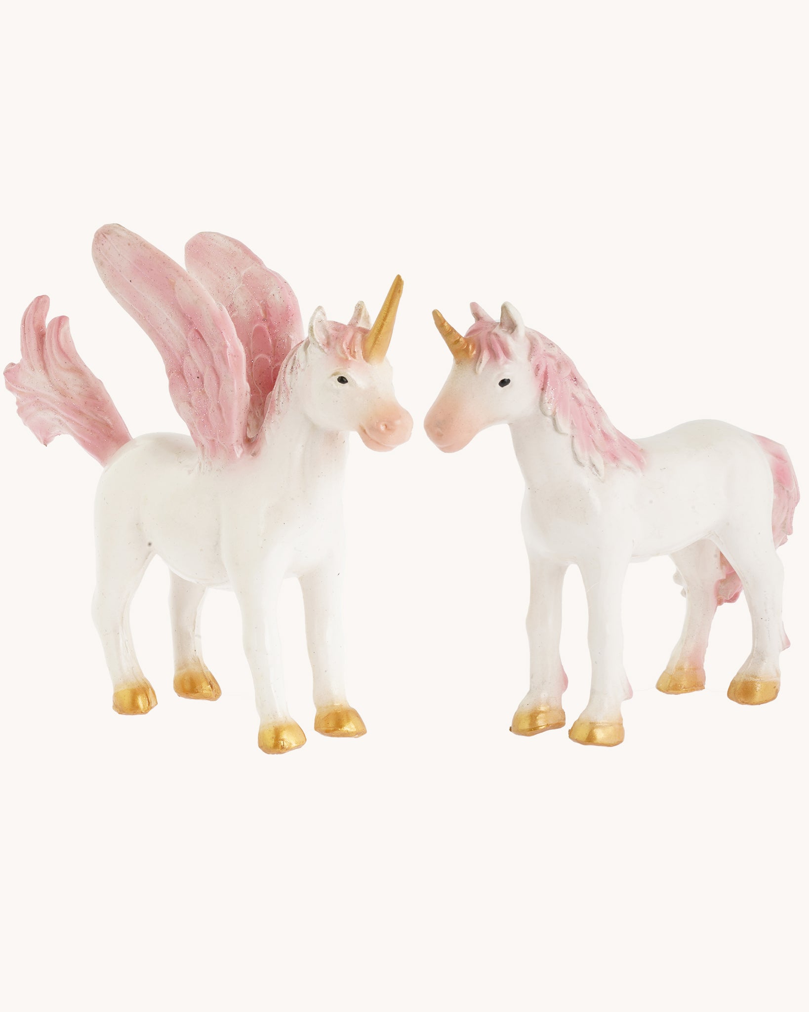 The Green Rubber Toys Rainbow Unicorn and Pegasus is a 2-pack of natural rubber, eco-friendly toy mythical horse figures with white bodies and pink details on the wings, tails and mane and golden hooves and horns. The image is on a cream background