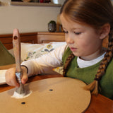 A little girl painting her VAH DIY wooden toy shield with white paint. 