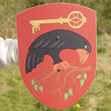 VAH Crovus toy shield, wooden with a crow, key and branch on red background, for battle dress up.