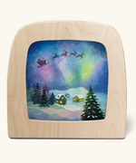 Toverlux silhouette of Father Christmas flying through the sky with Northern lights, snowy houses and Christmas trees, for December and Christmas Eve celebrations.