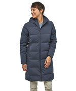 Person wearing a long blue puffer coat on a white background