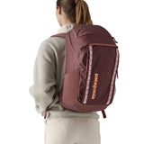 A view of a woman wearing The Patagonia Black Hole Pack 32 litre capacity backpack in dulse mauve colour.