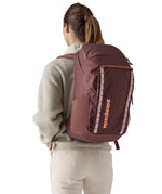 A view of a woman wearing The Patagonia Black Hole Pack 32 litre capacity backpack in dulse mauve colour.
