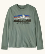 Patagonia Kids organic cotton Long-Sleeved Graphic T-Shirt in Cover Green. A sage green body with a vintage-style Patagonia Fitz Roy Foothills logo on the chest.