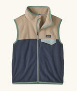 Patagonia Kids Micro D Snap-T Fleece Vest in Smolder Blue with Oar Tan. Navy blue lower body panel, camel beige upper panel, and sage green binding with a matching chest pocket flap.