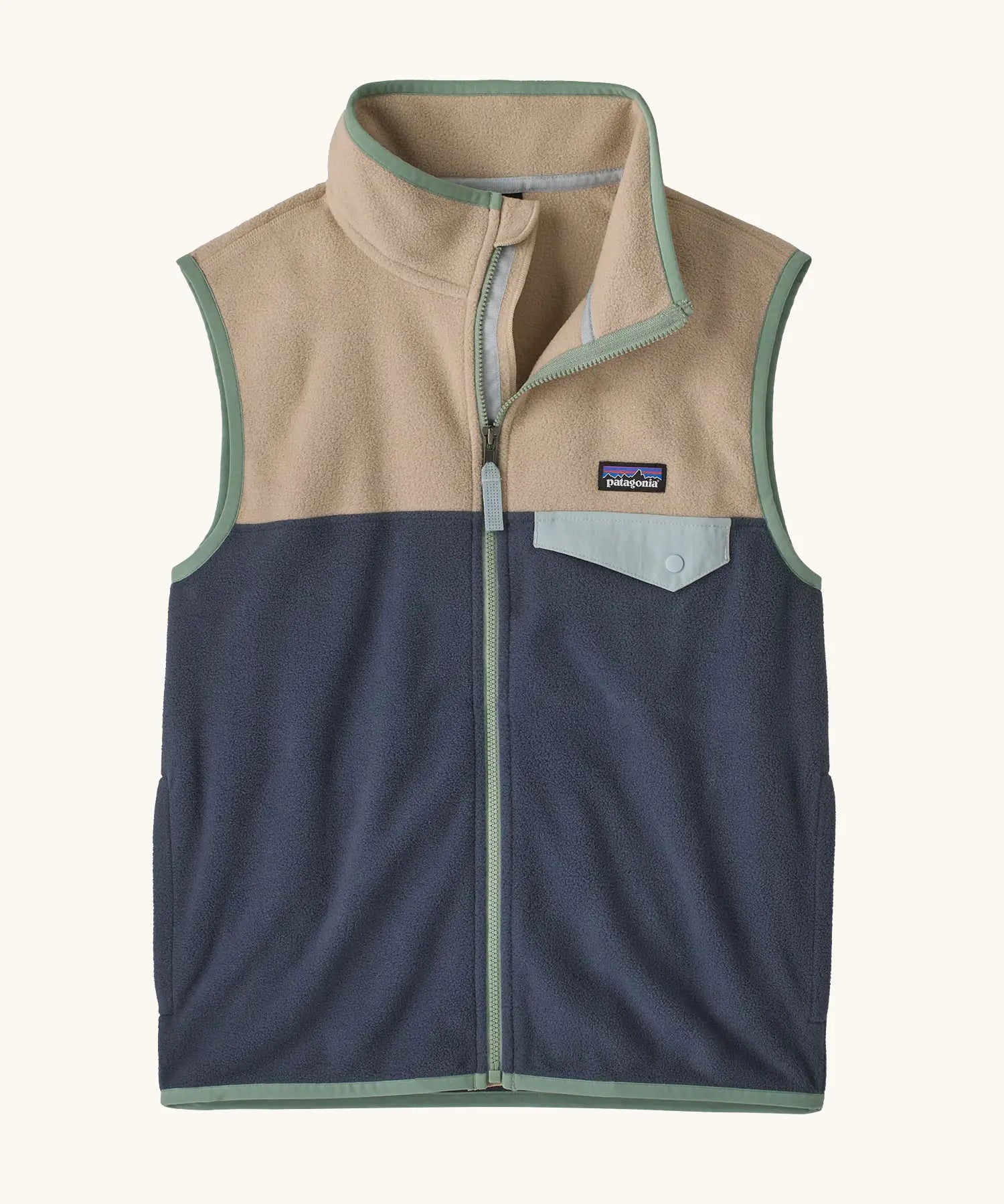 Patagonia Kids Micro D Snap-T Fleece Vest in Smolder Blue with Oar Tan. Navy blue lower body panel, camel beige upper panel, and sage green binding with a matching chest pocket flap.