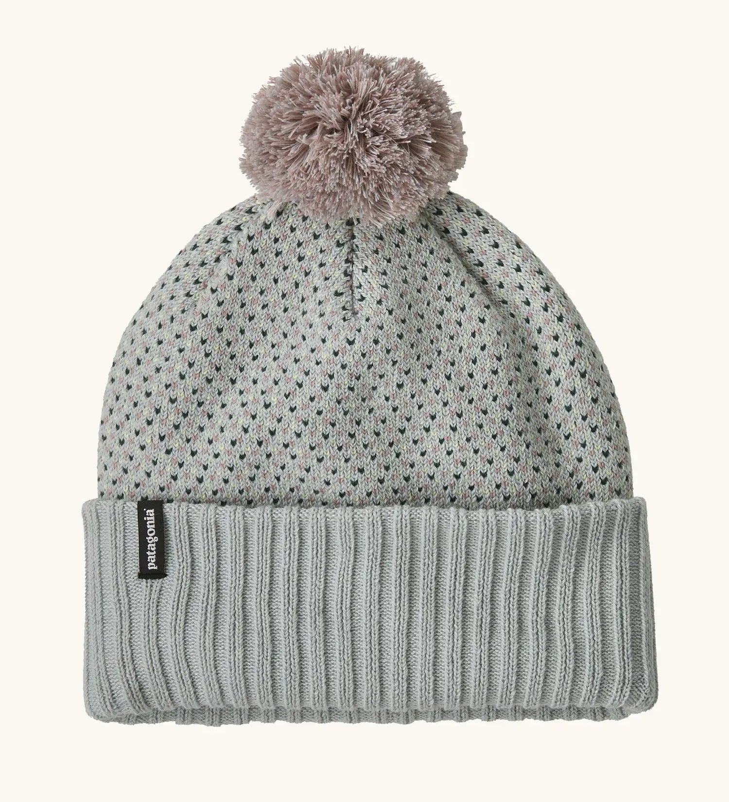 Patagonia Kids Powder Town Beanie in Confetti: virtually blue. A Light grey knit with pink and navy dots, a rib knit cuff, and a pale pink pom-pom on top. With a small vertical Patagonia logo on the cuff.