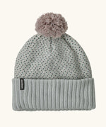 Patagonia Kids Powder Town Beanie in Confetti: virtually blue. A Light grey knit with pink and navy dots, a rib knit cuff, and a pale pink pom-pom on top. With a small vertical Patagonia logo on the cuff.