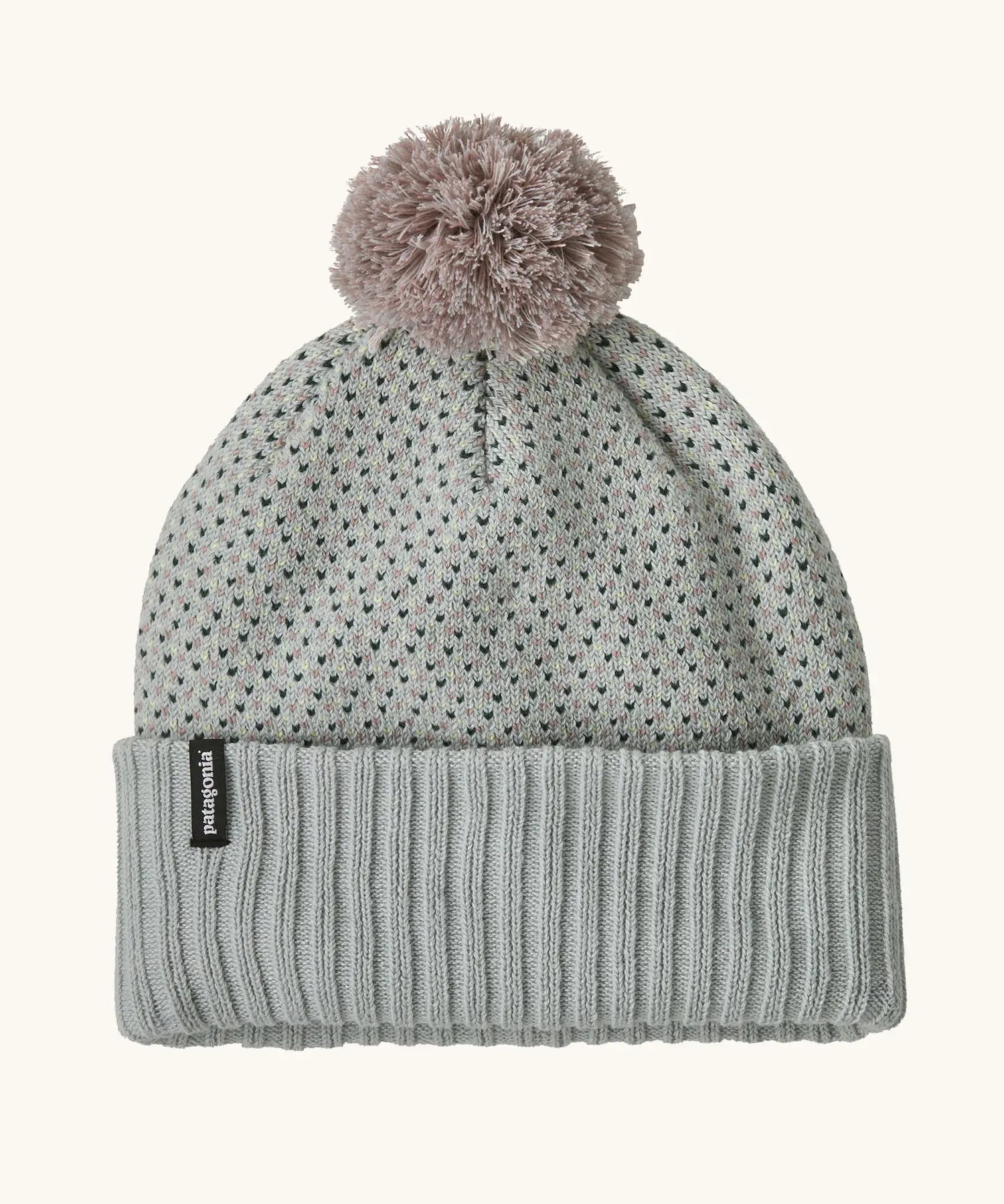 Patagonia Kids Powder Town Beanie in Confetti: virtually blue. A Light grey knit with pink and navy dots, a rib knit cuff, and a pale pink pom-pom on top. With a small vertical Patagonia logo on the cuff.