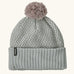 Patagonia Kids Powder Town Beanie in Confetti: virtually blue. A Light grey knit with pink and navy dots, a rib knit cuff, and a pale pink pom-pom on top. With a small vertical Patagonia logo on the cuff.