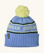 Patagonia Kids Powder Town Beanie in Park Stripe: Diver Blue. A pale blue knit with lime green 'Patagonia' woven around the head, a rib-knit cuff, and a lime green pom-pom on top. 