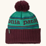 Patagonia Kids Powder Town Beanie in Park Stripe: Solo Teal. A teal knit with maroon 'Patagonia' woven around the head, a maroon rib-knit cuff, and a maroon pom-pom on top. 