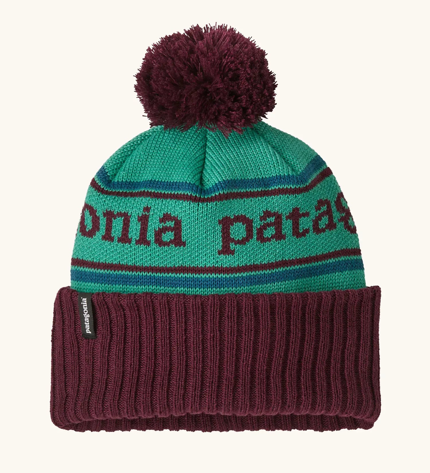 Patagonia Kids Powder Town Beanie in Park Stripe: Solo Teal. A teal knit with maroon 'Patagonia' woven around the head, a maroon rib-knit cuff, and a maroon pom-pom on top. 