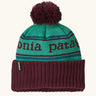Patagonia Kids Powder Town Beanie in Park Stripe: Solo Teal. A teal knit with maroon 'Patagonia' woven around the head, a maroon rib-knit cuff, and a maroon pom-pom on top. 