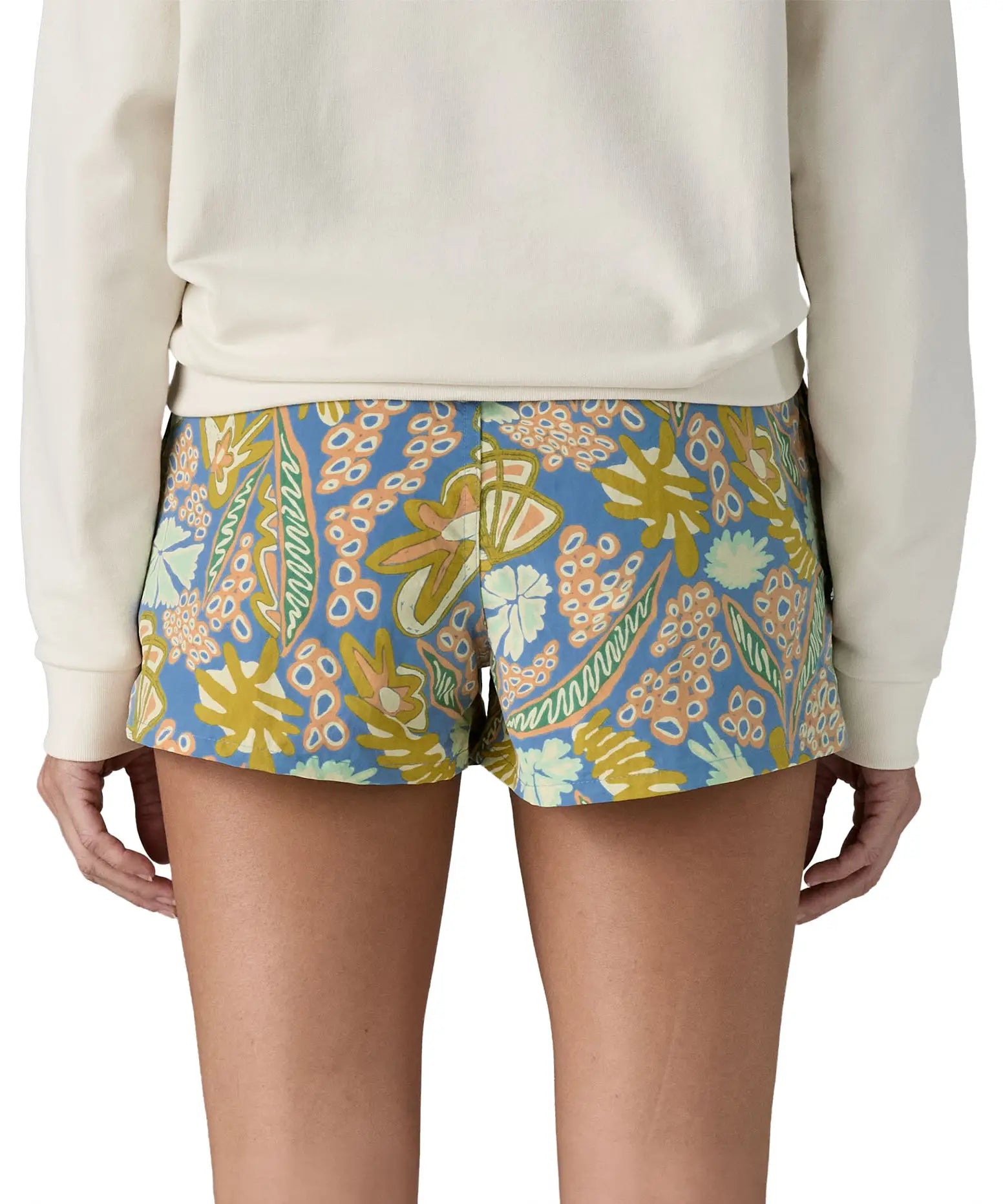 Back of woman wearing Patagonia's quick drying barely baggies shorts in blue with a repeating abstract floral design. 