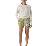 Woman wearing Patagonia's quick drying barely baggies shorts in blue with a repeating abstract floral design. Shorts have a regular fit