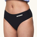 Side of model wearing the WUKA Teen Stretch Bikini Brief Period Pants showing the white branding 