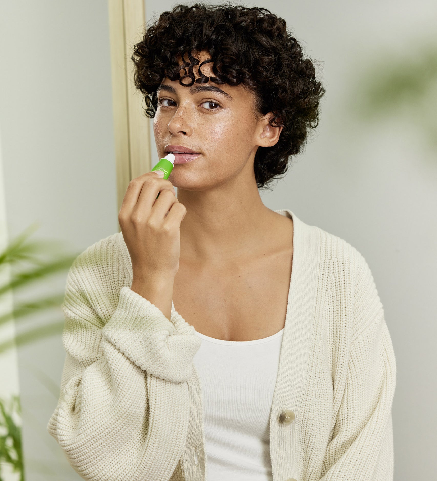 A woman applying the Weleda skin food lip balm on her lips. This balm is available at Babipur.