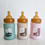 Hevea Glass Baby Bottle Wide Neck With Rubber Sleeve - 150ml in Seafoam Blue, Sand and Powder Pink