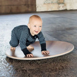 Wobbel 360, a wooden circular balance board toy, being played with by a baby.