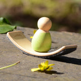 Mini Wooden Wobbel Balance Board for your peg dolls, a pocket-sized dollhouse size board, outside with a baby Nin on it.