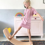 Wobbel original balance board, made from beech wood, being played with by young girl in a playroom.