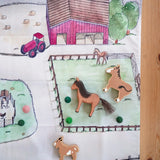 Wonderie cotton play cloth with farm design featuring a horse paddock with Ostheimer and Lanka Kade toy horses.