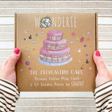 Wonderie cake play cloth box in hands. A three tier birthday play cloth with 60 Grapat wooden play food decoration pieces and paper invitations.