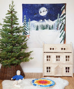 Wonderie Christmas Cotton Play Cloth, One Starry Winter's Night, a snowy forest scene with Santa and his sleigh in the Babipur playroom next to a PlanToys Victorian Dollhouse and Christmas tree.