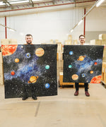 A wonderie solar space giant plat cloth next to the smallest solar space giant play cloth held by 2 adults