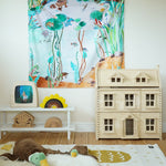Wonderie Play Cloth - Down By The Pond on a play room wall, with toys and a dolls house underneath