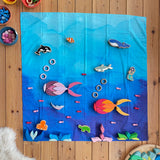 Wonderie organic cotton play cloth in blue used as an ocean in an under the sea play set up with Lanka Kade figures and Grimm's Lara building set.