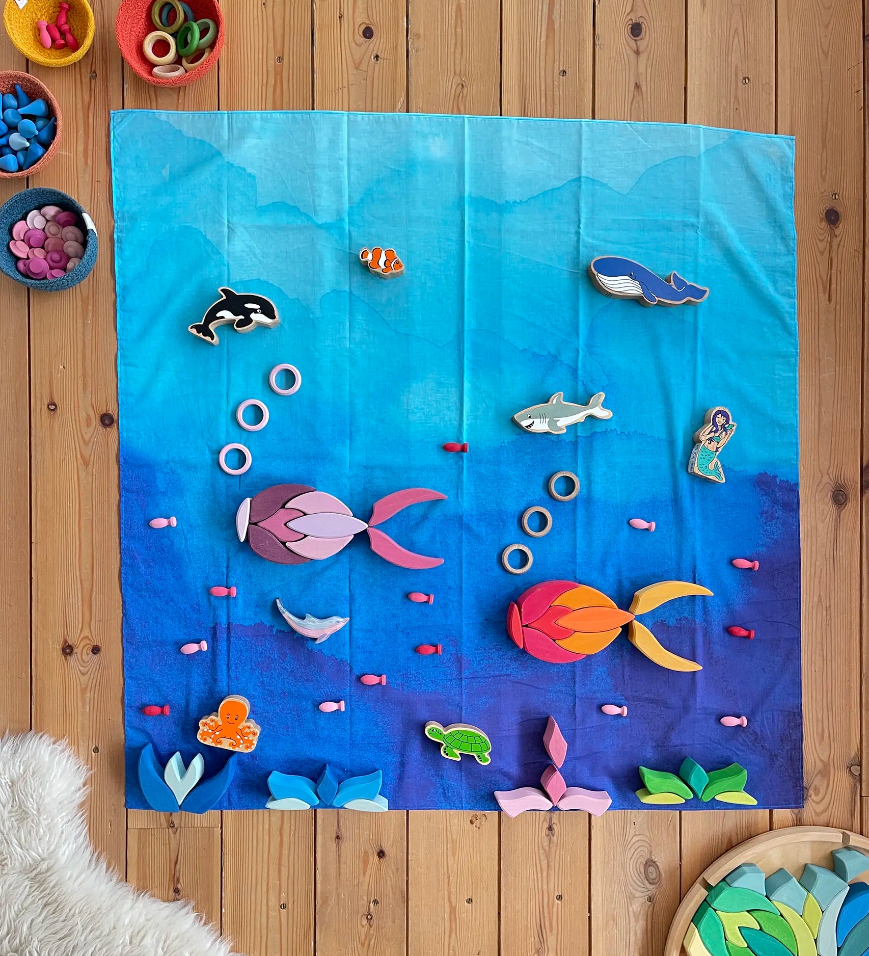 Wonderie organic cotton play cloth in blue used as an ocean in an under the sea play set up with Lanka Kade figures and Grimm's Lara building set.