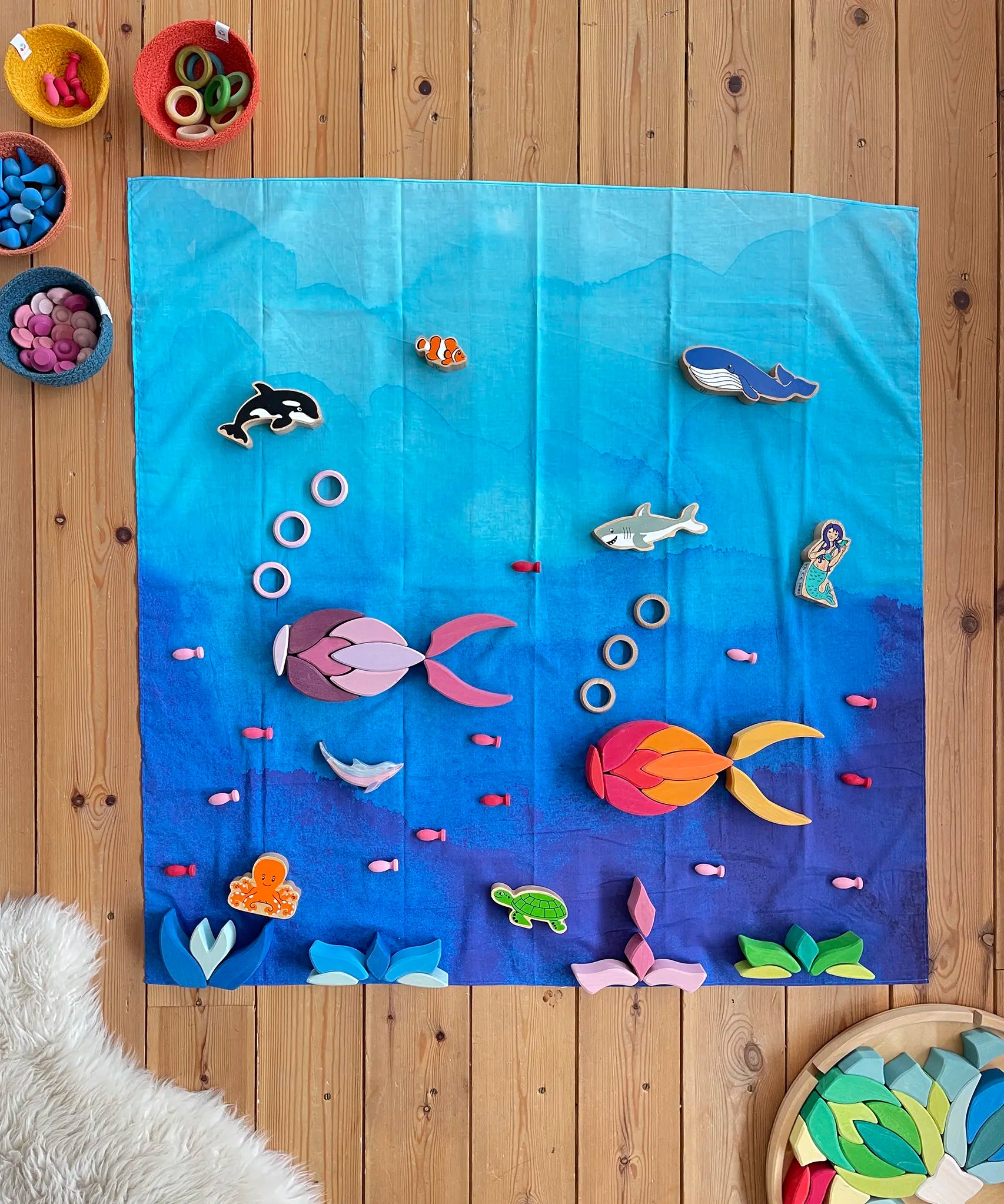 Wonderie organic cotton play cloth in blue used as an ocean in an under the sea play set up with Lanka Kade figures and Grimm's Lara building set.