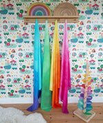 Wonderie organic cotton play cloths in green, blue, yellow and pink in the Babipur playroom next to a Magic Wood marble tree and Grimm's rainbows.