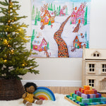 Wonderie Play Cloth - Gingerbread Lane is hung up on a wall behind a Christmas Tree on the left hand side of the photo and various toys on the floor