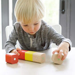 A child sat at a white table, playing with the Tegu Magnetic Wooden Blocks 