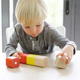 A child sat at a white table, playing with the Tegu Magnetic Wooden Blocks 