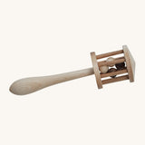 Wooden Story Nighthawk Rattle is a beautiful, wooden musical and sensory rattle which children can roll along the floor, shake or rub between their palms. The rattle head is like a little wooden cage with wooden balls inside, on top of a wooden stick that gets wider towards the end. The image is on a cream background