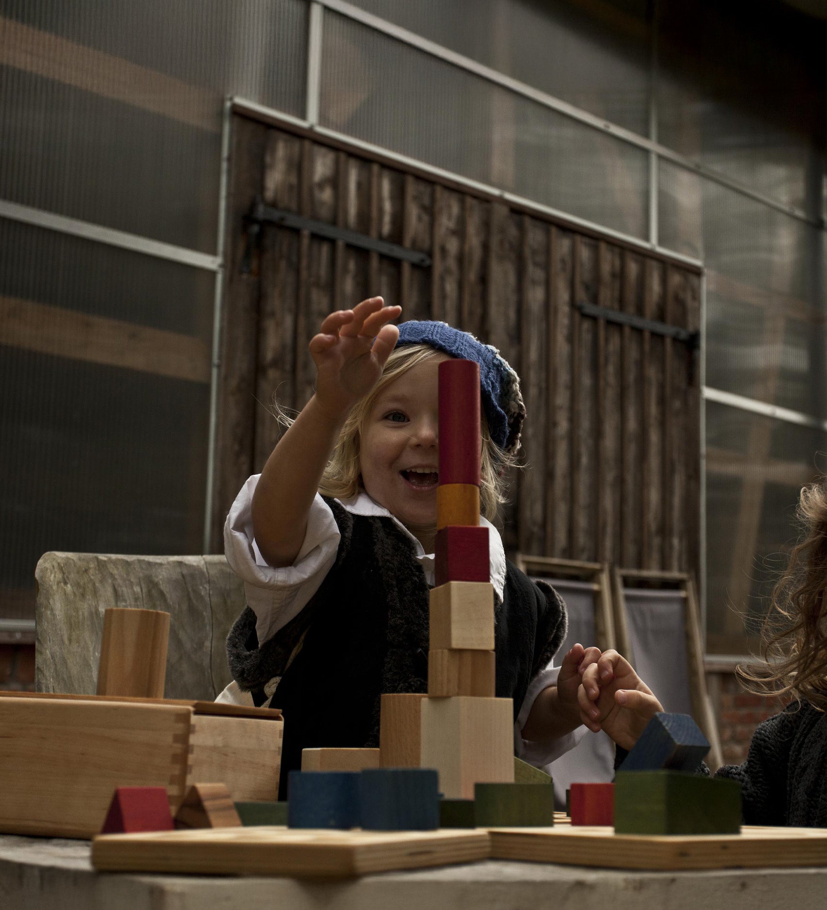 A child playing with some of the pieces from the Wooden Story rainbow shape sorter box available at Babipur. 
