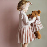A child playing with the Wooly Organic soft teddy bear in caramel brown with a pink tutu available at Babipur.