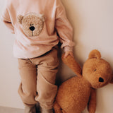A close up of a child holding the Wooly Organic soft teddy bear in caramel brown by the hand. Teddy bear available at Babipur.