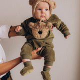 A baby wearing the Wooly Organic embroidered sweater in tea leaf /savannah available at Babipur showing the popper fastener detail